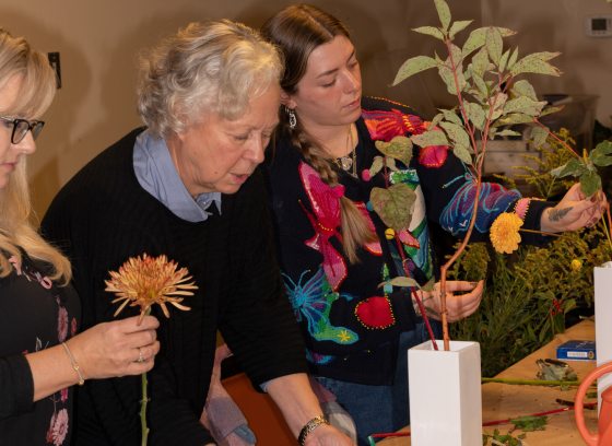 Three people standing at a table creating a floral design.