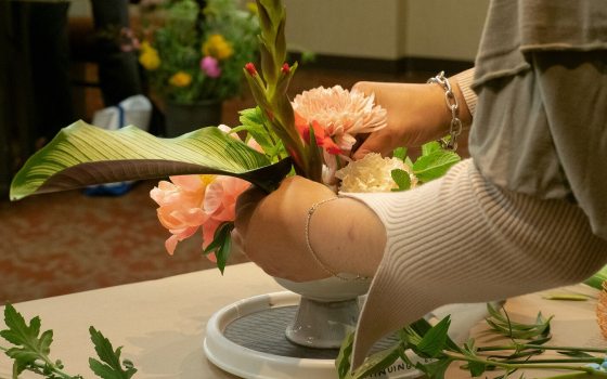 A person creating a floral arrangement in a classroom setting.