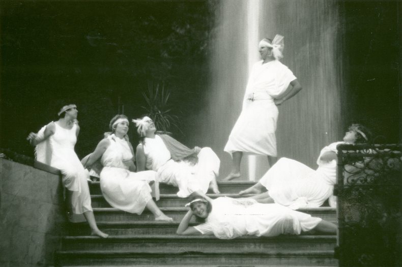 Students dressed in all white pose on a set of stairs mimicking a vintage photo