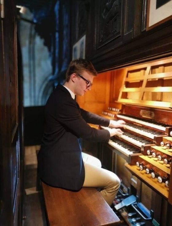 a teenager sitting at an organ console playing the keys