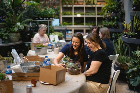People sitting around a table in a plant shop doing a workshop. 