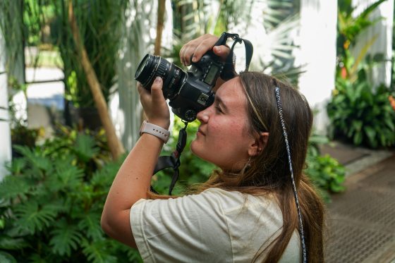 A person taking a photo with a large camera in the Longwood Conservatory.