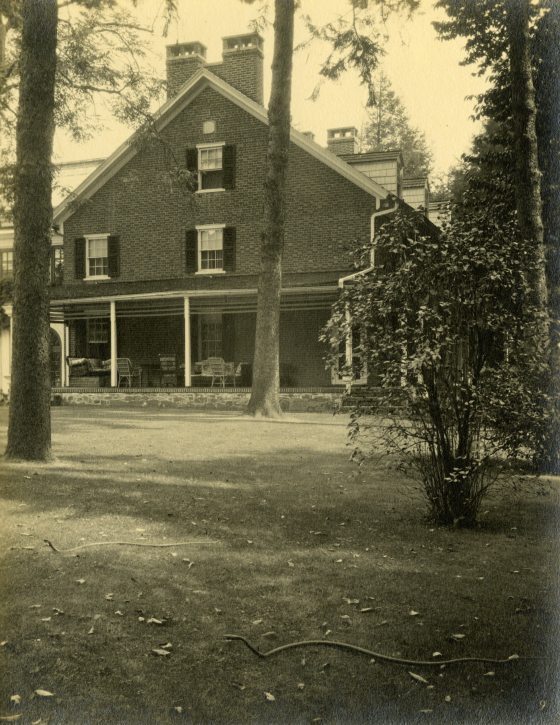 A sepia toned image of a farmhouse surrounded by trees.