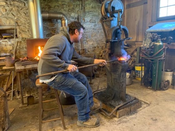 A person heating up black iron over a kiln. 